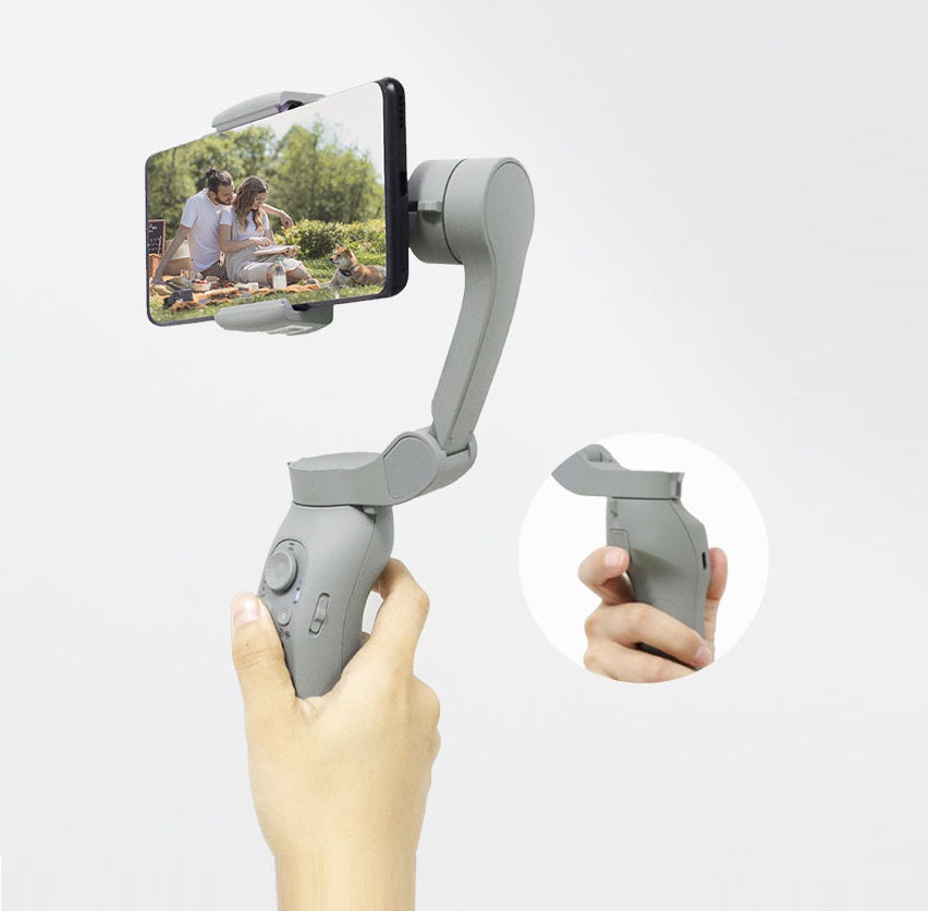 Hand holding a smartphone with a gimbal stabilizer attached on a white background
